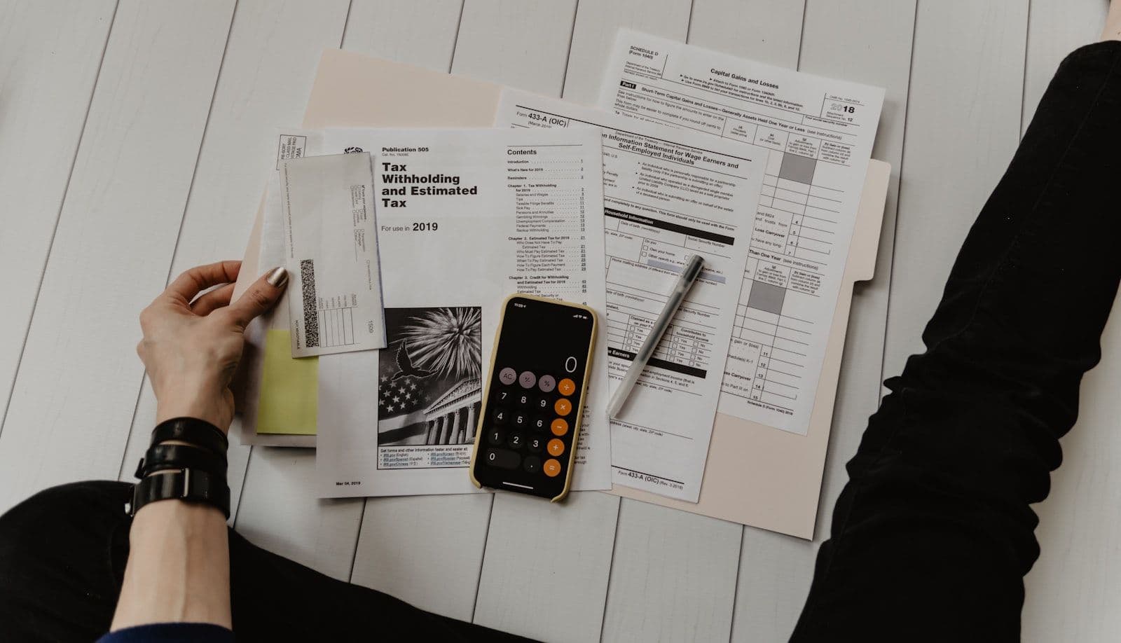 Calculadora e papelada sobre mesa de trabalho